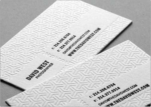 Close-up of premium business cards featuring a detailed geometric blind debossing pattern pressed into thick paper stock.