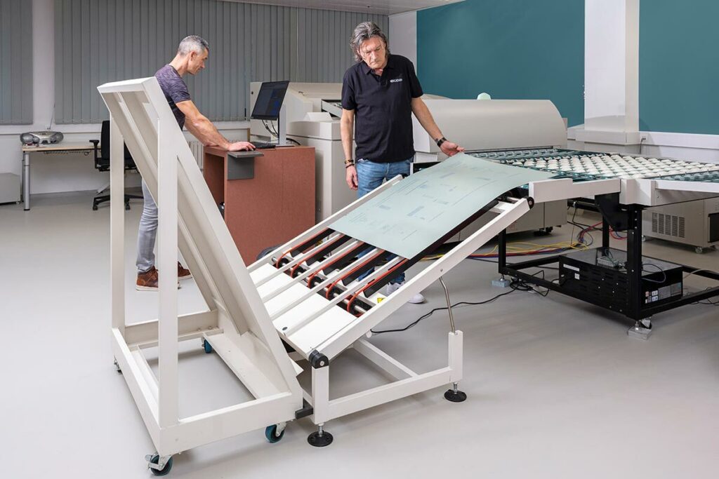 Prepress operators managing an automated Computer-to-Plate (CTP) platesetter, outputting high-resolution aluminum printing plates for an offset press