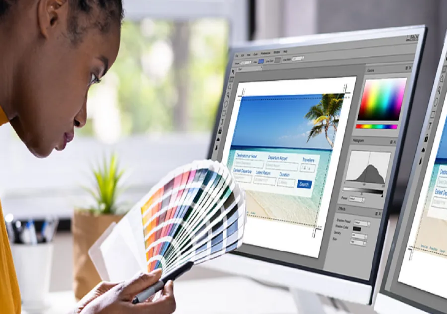A prepress operator performing digital preflighting and color separation, comparing a digital print layout on a dual-monitor setup against physical CMYK and Pantone color swatches.