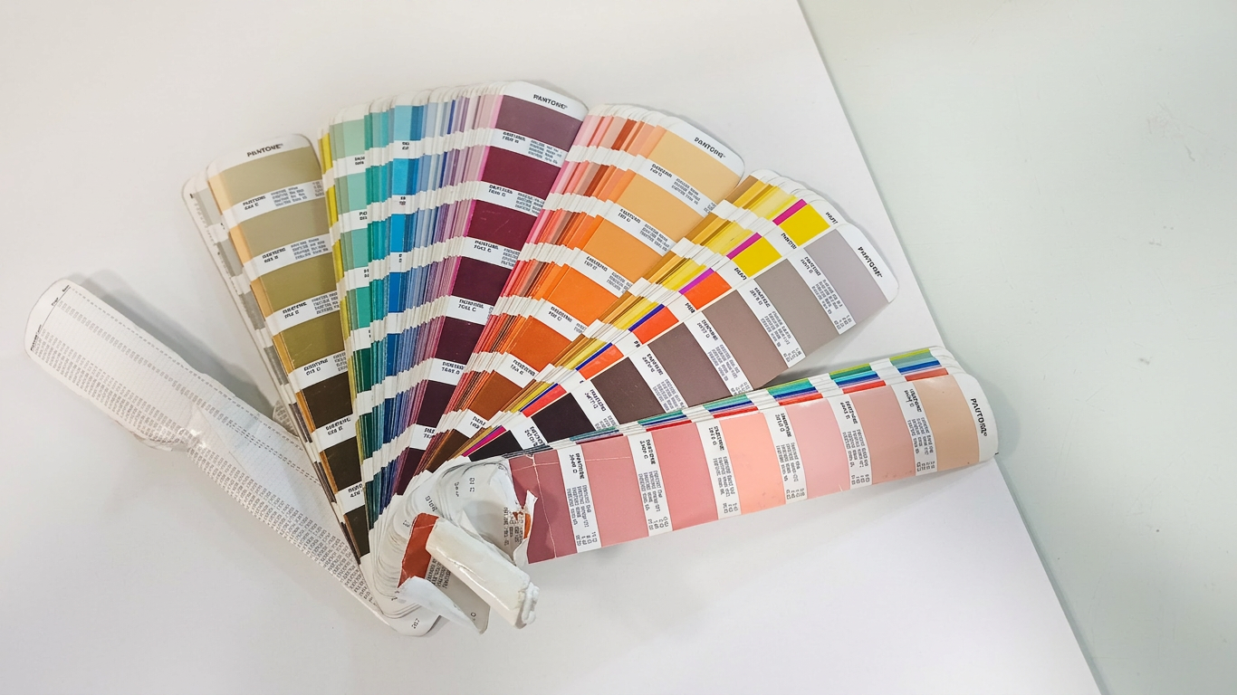A fanned-out Pantone Matching System (PMS) formula guide showing various color swatches, reference codes, and precise ink mixing ratios used by press operators in offset printing.