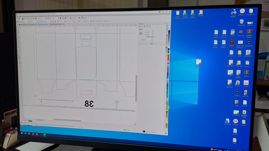 A prepress operator's workstation displaying a vector packaging dieline and crop marks in layout software, preparing a structural folding carton design for offset printing.