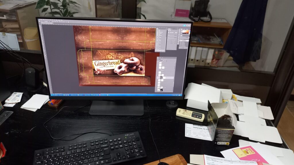 A prepress workstation monitor displaying a food packaging design in raster graphics software, highlighting the layers and channels panels used for precise CMYK color separation.